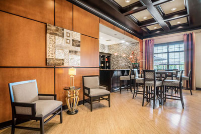 Residents' center lounge with comfortable chairs, round tables, and hanging artwork