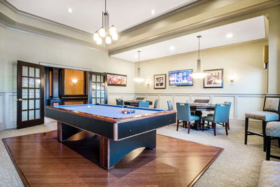 Resident entertainment area with billiard table, smaller card tables, and artwork on the walls